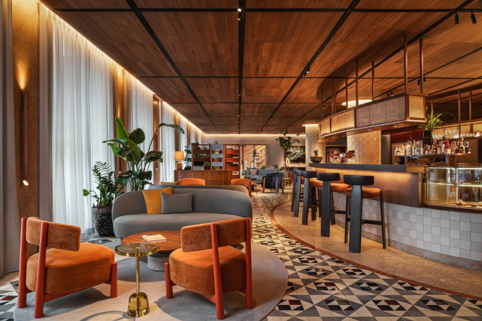 Stylish interior of a modern café featuring colorful furniture, a well-lit bar area, and decorative plants.