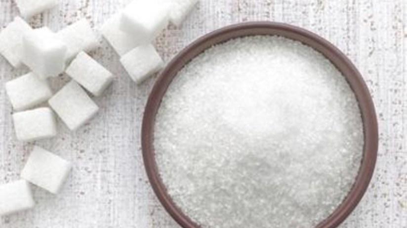 Sugar granules close-up on a wooden surface, highlighting texture and crystal structure, relevant to sugar industry news.