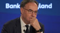 Andrew Bailey, Governor of the Bank of England, in a suit and tie, looking thoughtful during a press conference.