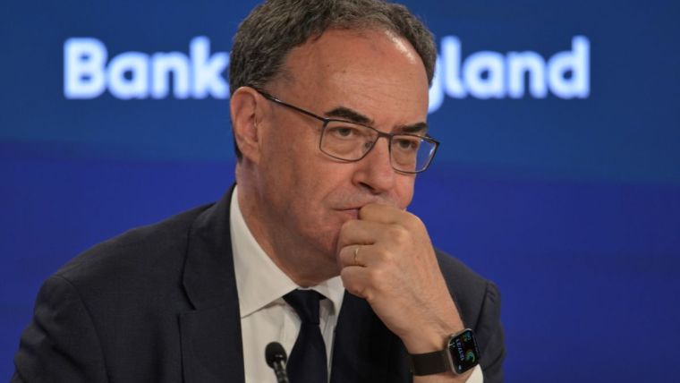 Andrew Bailey, Governor of the Bank of England, in a suit and tie, looking thoughtful during a press conference.