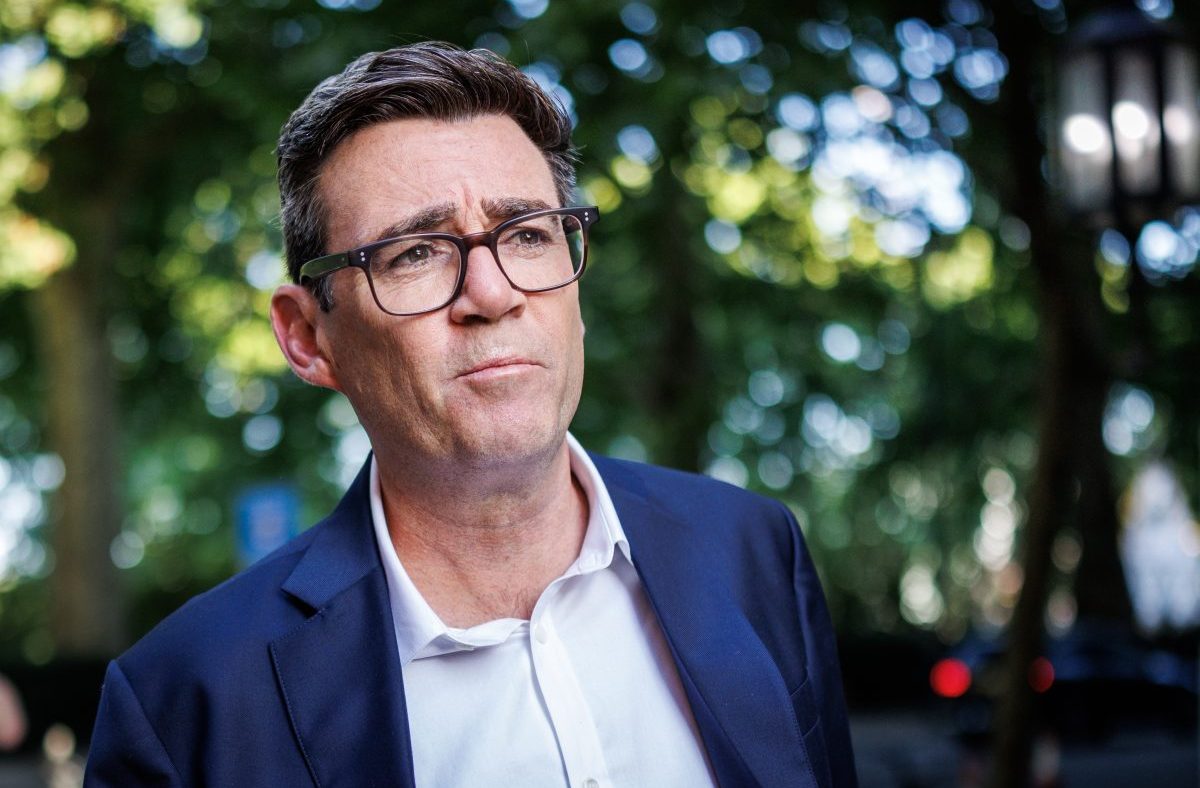 Andy Burnham speaking at a press conference, expressing confidence despite challenges, highlighting leadership and resilie...
