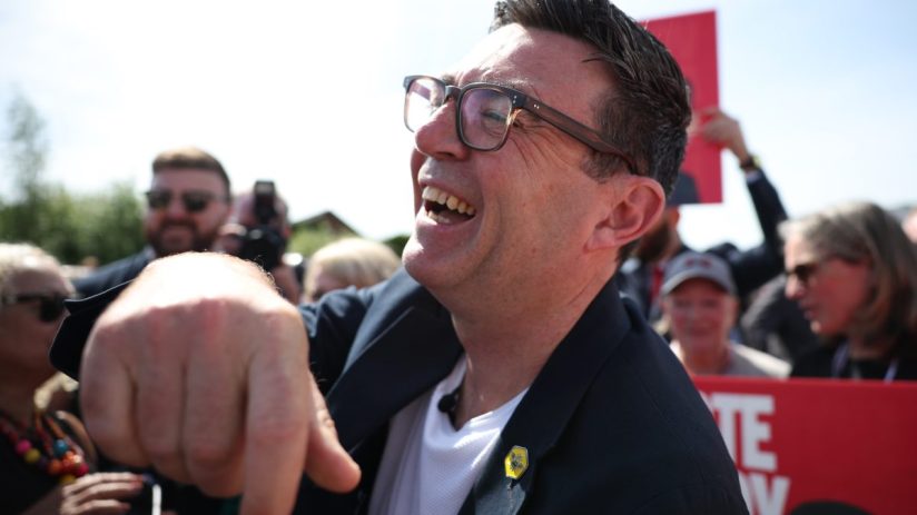 Andy Burnham laughing outdoors in a candid moment, May 2026, capturing a lighthearted political event atmosphere.