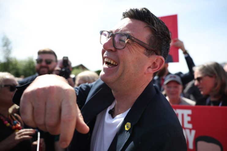 Andy Burnham laughing outdoors in a candid moment, May 2026, capturing a lighthearted political event atmosphere.