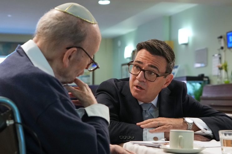 Andy Burnham, Mayor of Greater Manchester, discussing social care with an elderly man wearing a yarmulke.