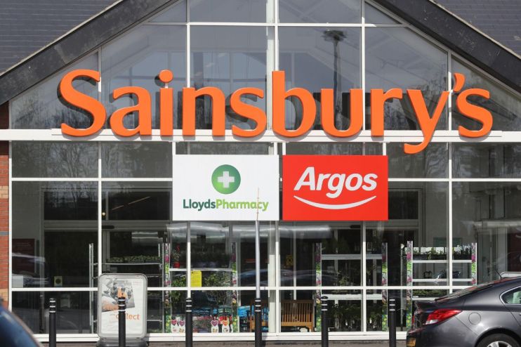 Sainsburys supermarket entrance with prominent Argos and Lloyds Pharmacy signs, reflecting the companys acquisitions.