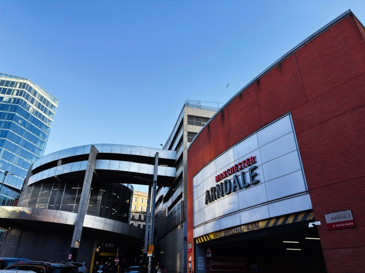 Manchester Arndale shopping centre entrance with Manchester Arndale sign, red brick, and modern glass buildings.