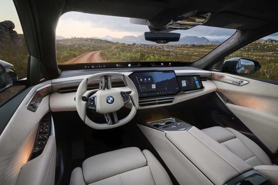 Modern BMW X5 interior with a panoramic view, beige leather seats, and large digital displays
