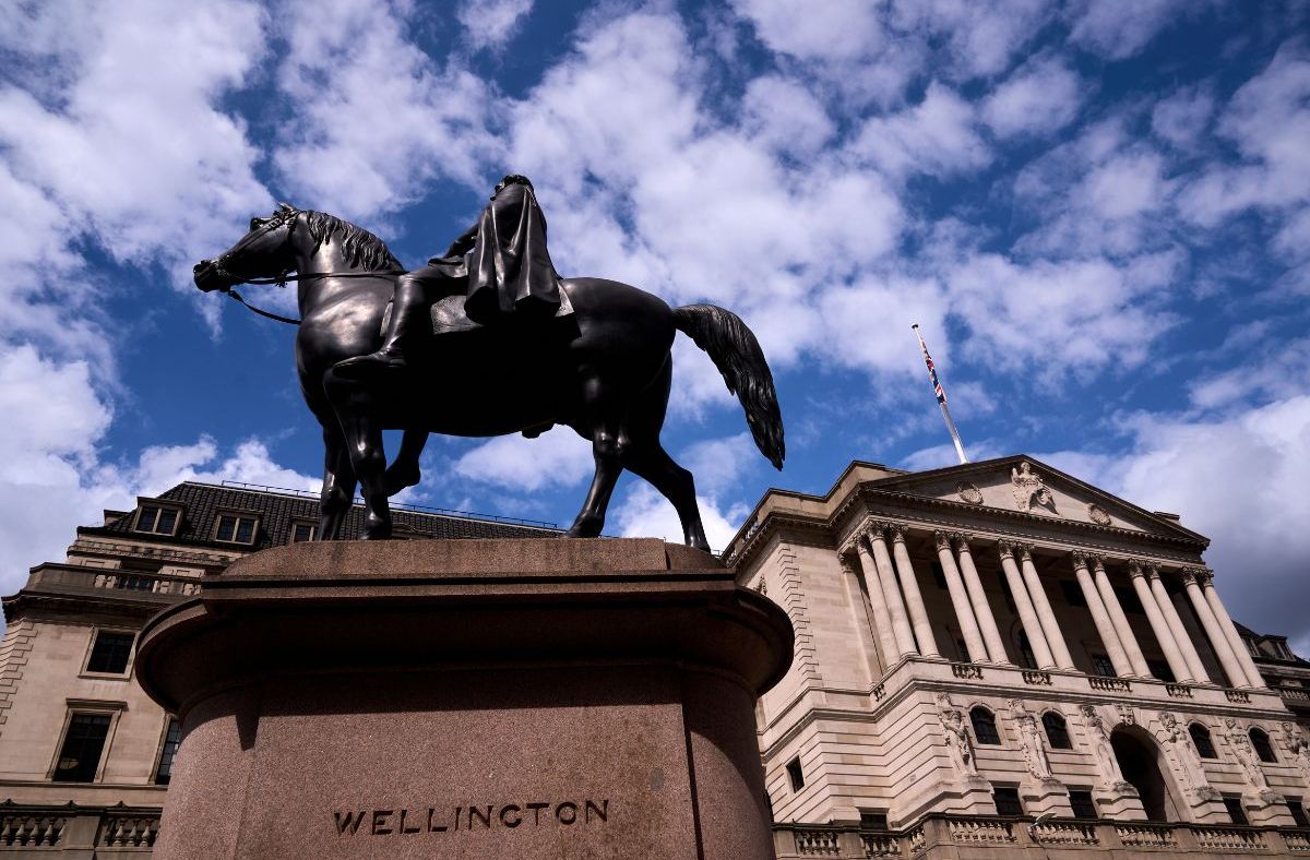 Wellington statue in front of the Bank of England building with a British flag flying under a cloudy sky