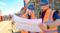 Barratt and Redrow partnership announcement showcasing executives shaking hands in a modern office setting