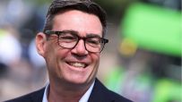 Andy Burnham, Mayor of Greater Manchester, smiling and wearing glasses outdoors.