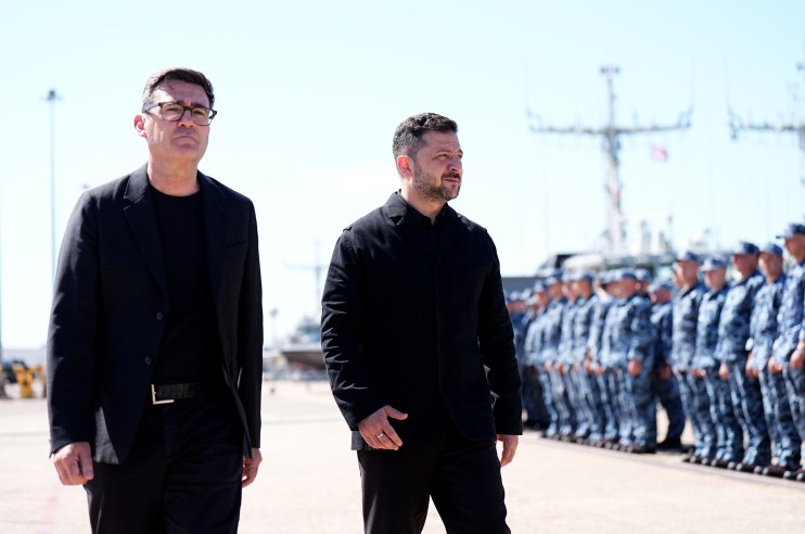 Andy Burnham and Volodymyr Zelenskyy walking, with uniformed military personnel in background.
