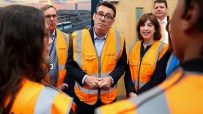 Andy Burnham in a hi-vis vest, with other officials, during a visit to a facility.