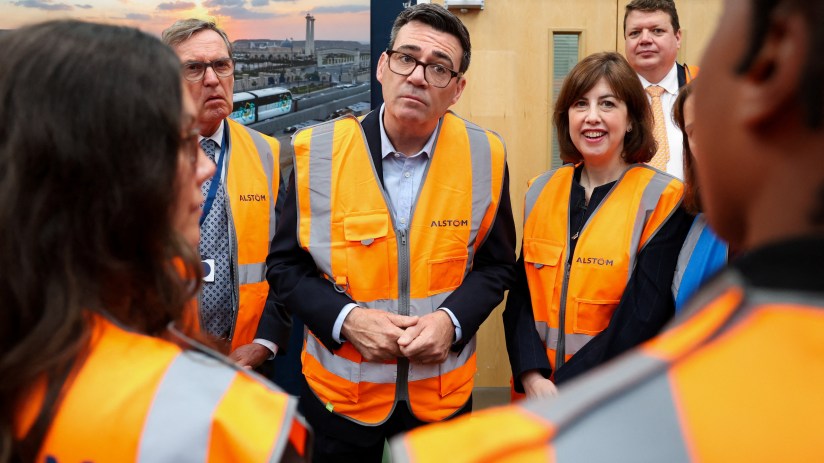 Andy Burnham in a hi-vis vest, with other officials, during a visit to a facility.