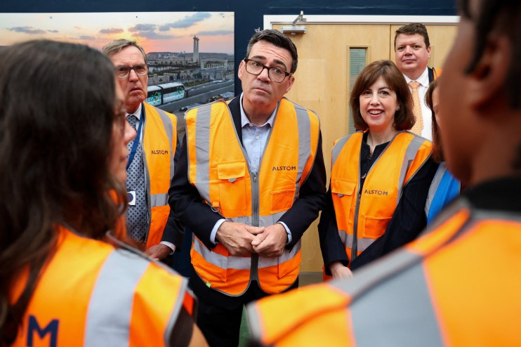 Andy Burnham in a hi-vis vest, with other officials, during a visit to a facility.