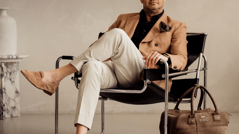 David Collyer, CEO of Swissport, sitting in a black leather chair with a brown travel bag beside him.