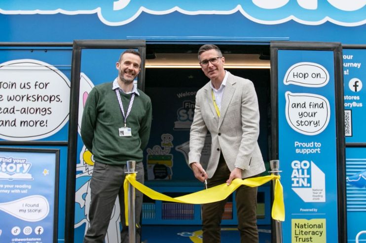 Gavin Peck (right) cuts a yellow ribbon with a man next to him, celebrating the StoryBus launch.