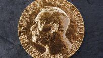 Close-up of a golden Nobel Prize medal featuring Alfred Nobels profile on a dark, textured background.