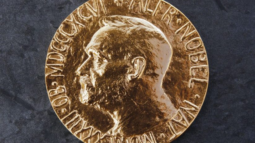 Close-up of a golden Nobel Prize medal featuring Alfred Nobels profile on a dark, textured background.