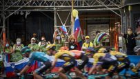 Cycling fans, some in green Feel Slovenia shirts, cheer cyclists with Slovenian flags.