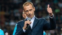 Aleksander Ceferin speaking into a microphone and giving a thumbs-up, wearing a suit at a public event