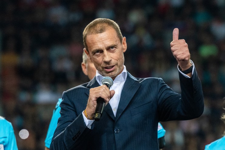 Aleksander Ceferin speaking into a microphone and giving a thumbs-up, wearing a suit at a public event