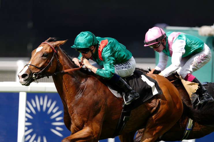 Jockey in a green racing silks riding a brown horse during a horse race, with another jockey in pink behind