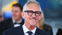 Gary Lineker in a suit and tie, smiling with glasses and a goatee, against a blurred background.