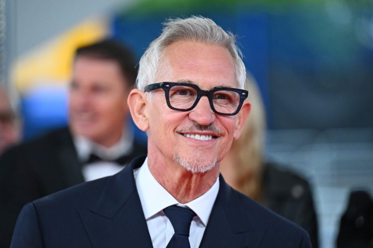 Gary Lineker in a suit and tie, smiling with glasses and a goatee, against a blurred background.