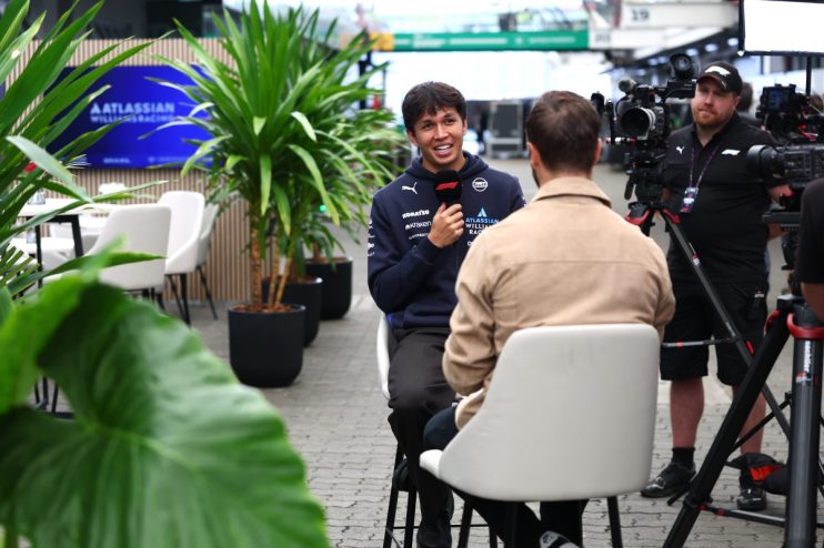 Alex Albon of Williams Racing giving an interview, with a camera crew nearby and Atlassian branding visible.