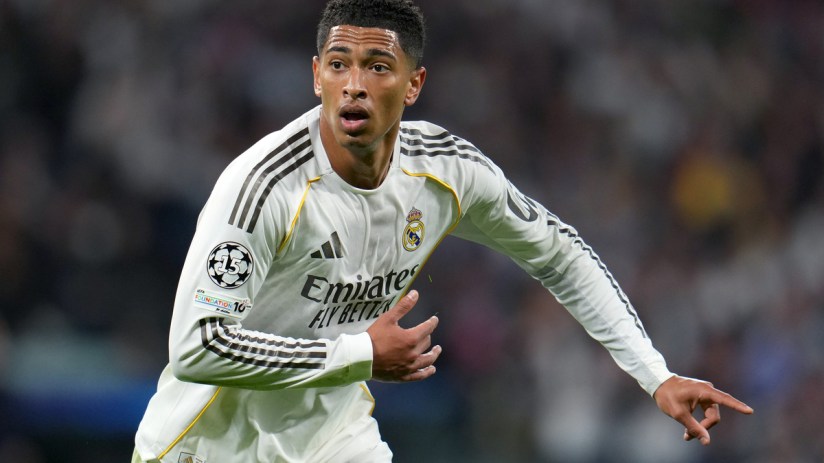 Jude Bellingham in a white Real Madrid jersey with black stripes, looking focused on the field during a match.