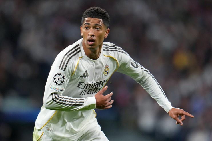 Jude Bellingham in a white Real Madrid jersey with black stripes, looking focused on the field during a match.