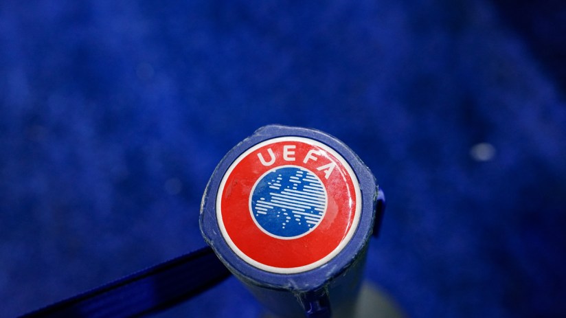 Close-up of a blue and red UEFA logo on a sports equipment handle against a blurred blue background