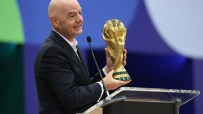 Gianni Infantino holding the FIFA World Cup trophy while speaking at a podium.