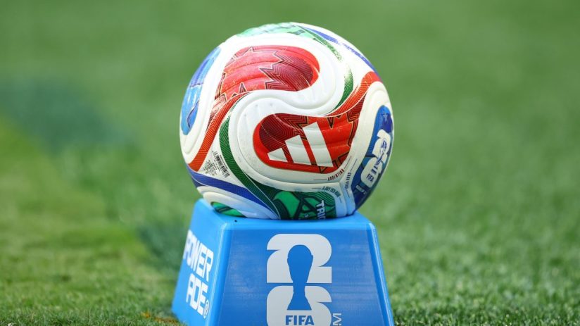 FIFA World Cup 2026 soccer ball on a blue stand with the FIFA logo, on a green grass field.