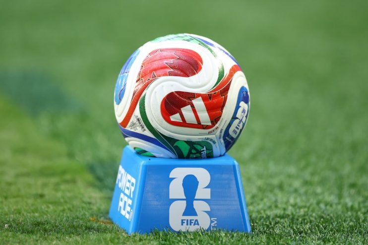 FIFA World Cup 2026 soccer ball on a blue stand with the FIFA logo, on a green grass field.