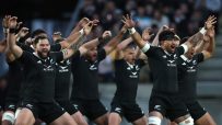 New Zealand All Blacks rugby players performing the Haka pre-game with arms raised and intense expressions