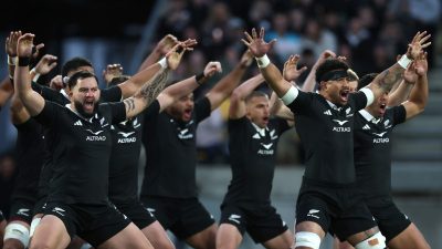New Zealand All Blacks rugby players performing the Haka pre-game with arms raised and intense expressions