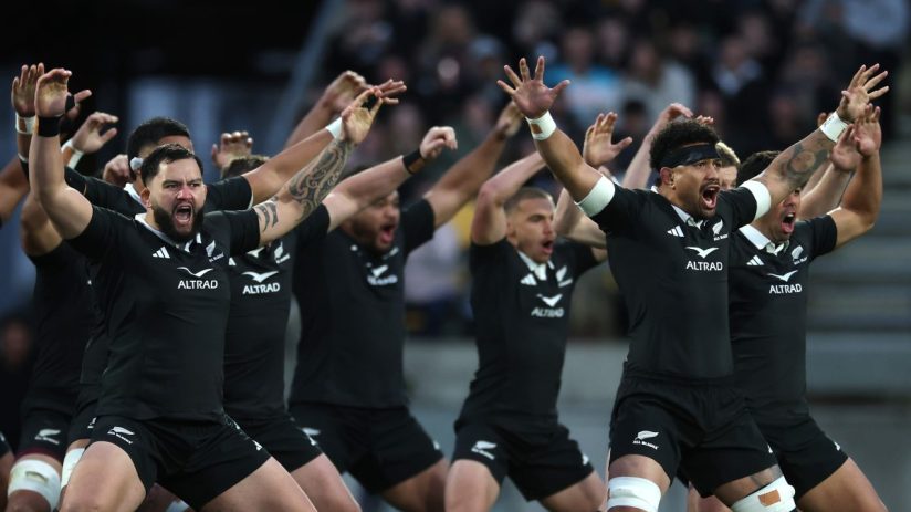 New Zealand All Blacks rugby players performing the Haka pre-game with arms raised and intense expressions