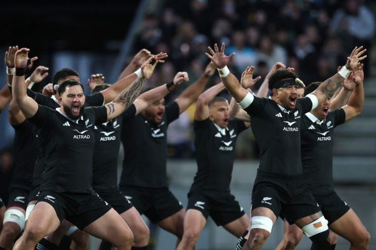 New Zealand All Blacks rugby players performing the Haka pre-game with arms raised and intense expressions