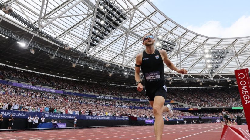 Josh Kerr winning an athletics race at the London Stadium, with cheering crowds in the background.