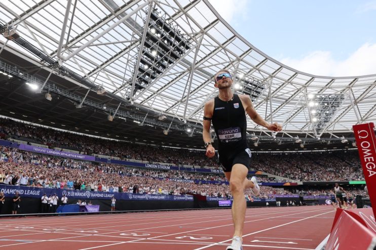 Josh Kerr winning an athletics race at the London Stadium, with cheering crowds in the background.