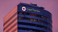 Grant Thornton office building exterior at dusk with illuminated logo and windows, purple sky.