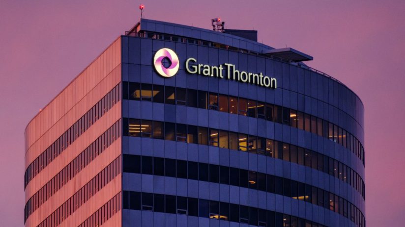 Grant Thornton office building exterior at dusk with illuminated logo and windows, purple sky.