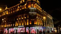 Harvey Nichols luxury department store at night, illuminated by golden lights and festive window displays.