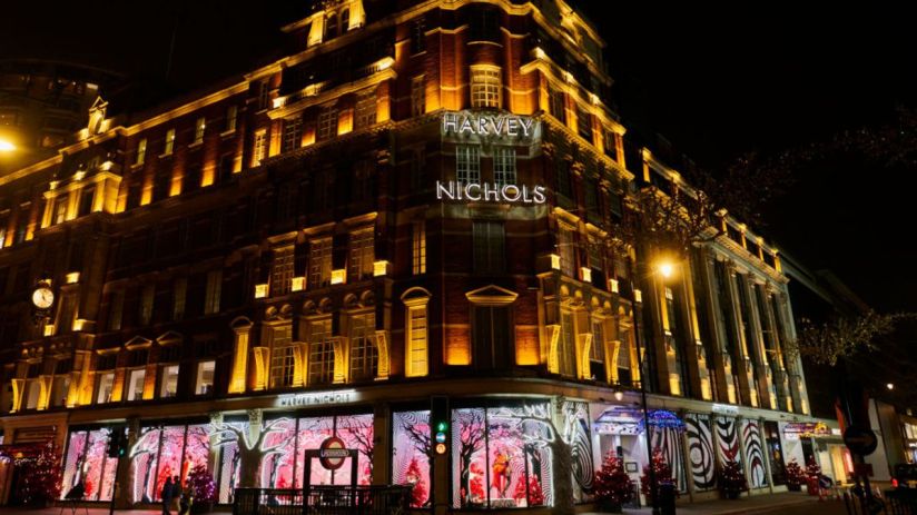 Harvey Nichols luxury department store at night, illuminated by golden lights and festive window displays.