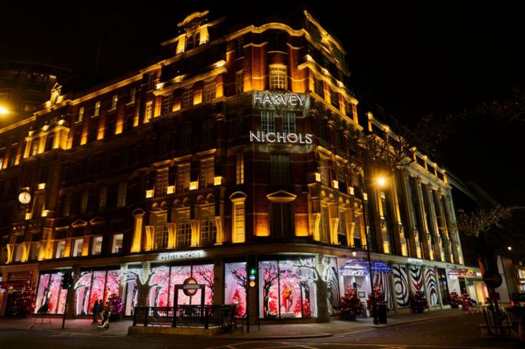 Harvey Nichols luxury department store at night, illuminated by golden lights and festive window displays.