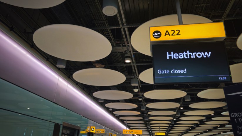 Heathrow airport terminal with Gate closed flight information display and modern ceiling design, highlighting infrastructure.
