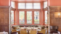 Dining room at The Connaught, featuring a large window, wooden paneling, and elegant seating.
