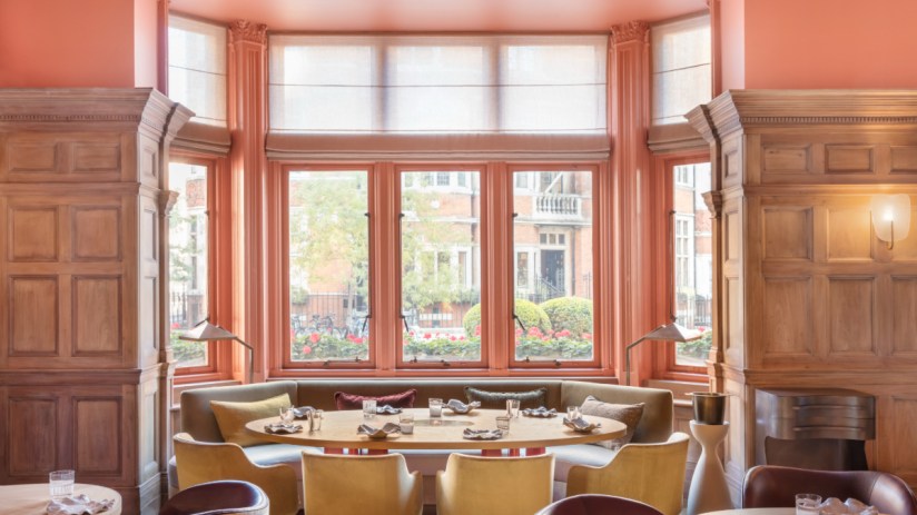Dining room at The Connaught, featuring a large window, wooden paneling, and elegant seating.