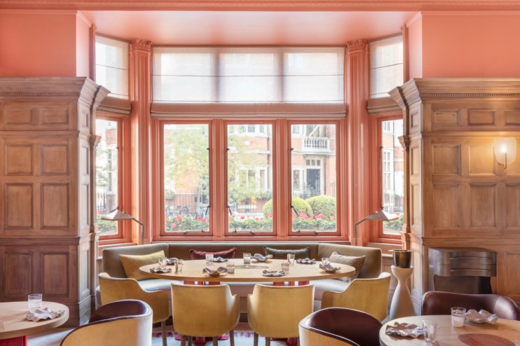 Dining room at The Connaught, featuring a large window, wooden paneling, and elegant seating.